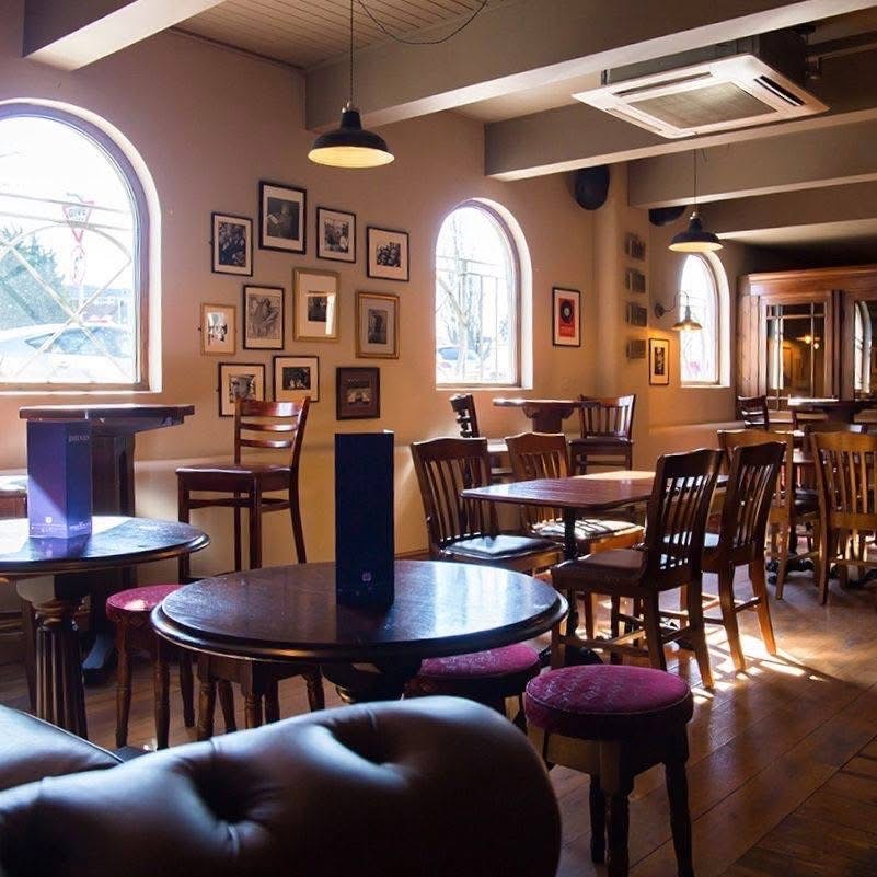 Tables and seating beside the arched windows at The Charles Bradlaugh